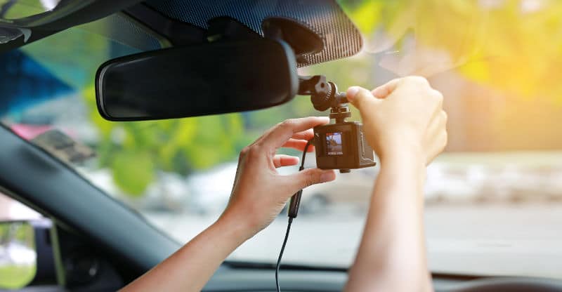 Person setting up a driver dash cam for automotive safety